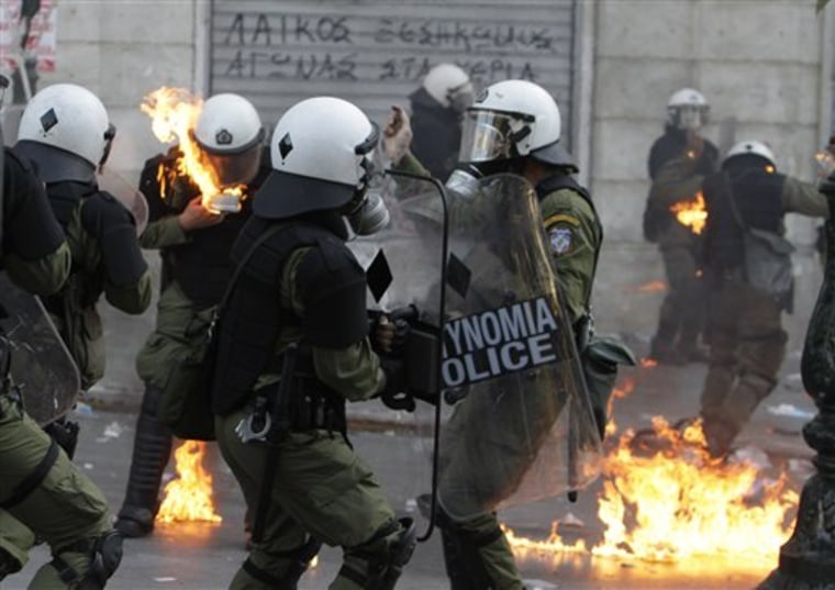 Riot policemen's clothing catches fire after protesters threw gasoline bombs during at them Thursday during clashes in Athens.  